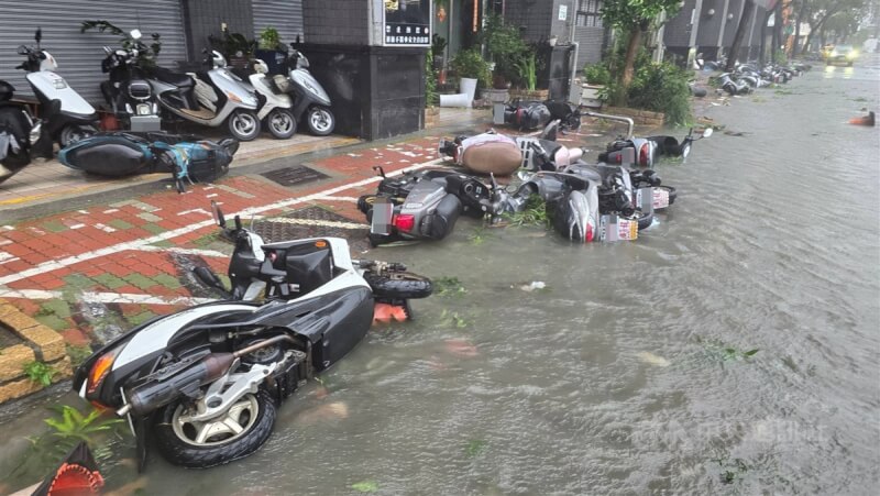 颱風凱米帶來驚人雨量，25日高雄市風雨不斷，三民區同盟路一帶路面積淹水，整排機車被強風吹倒。中央社記者董俊志攝 113年7月25日