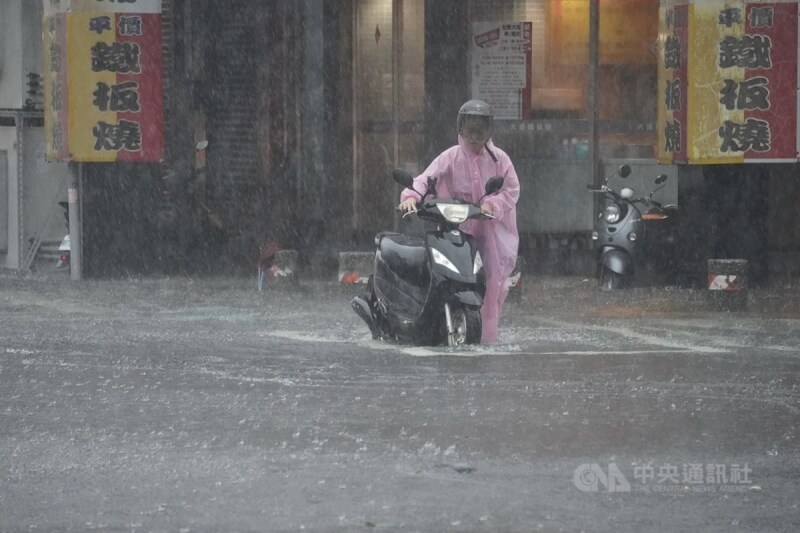 颱風凱米為中南部帶來大量雨水，25日高雄市三民區三鳳宮一帶水淹小腿肚，民眾牽著機車涉水而過。中央社記者董俊志攝 113年7月25日