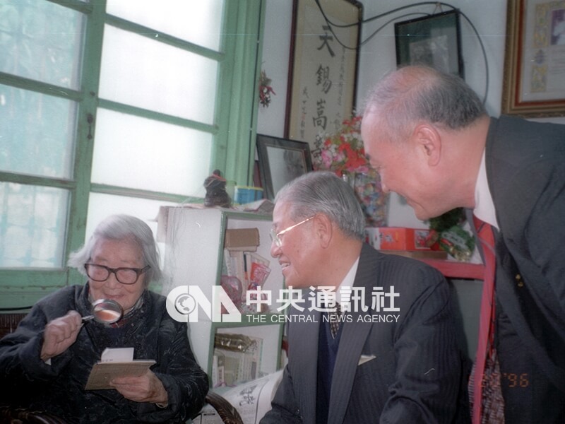 民國85年1月20日，李登輝總統（中）到成功大學探望高齡99歲的蘇雪林（左），蘇雪林以放大鏡仔細閱讀李總統親手寫的問候話語。中央社記者黃文儀攝 85年1月20日