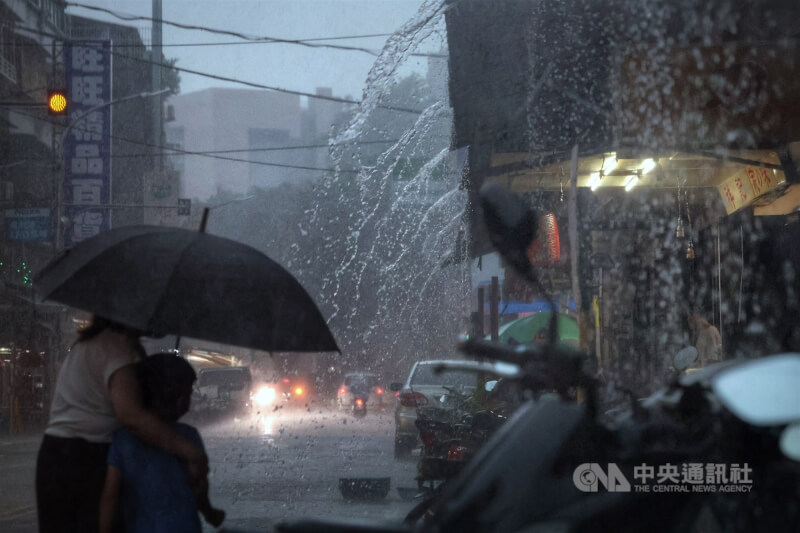 台北市內湖區午後下起大雷雨，民眾和小朋友共撐一把傘。（中央社檔案照片）