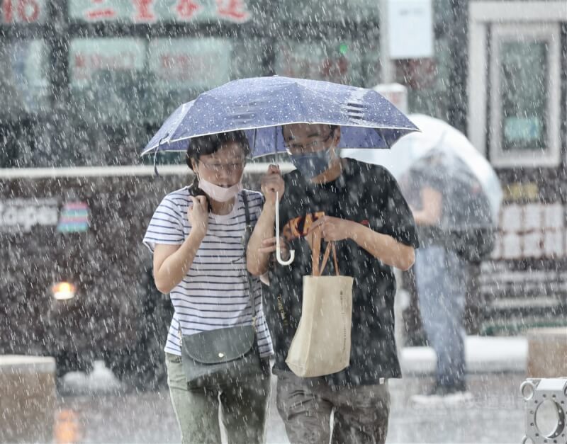 圖為台北車站附近民眾共撐一把傘遮雨。（中央社檔案照片）