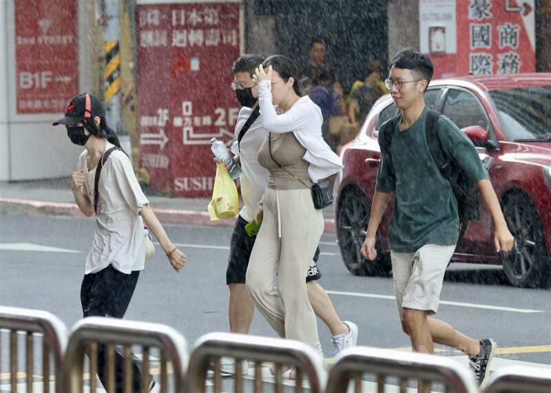 台北市午後下起雷陣雨，台北車站附近民眾沒帶傘出門，快步通過馬路。（中央社檔案照片）