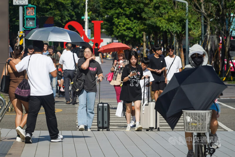 圖為台北市信義區豔陽高照，外出民眾撐傘防曬。（中央社檔案照片）