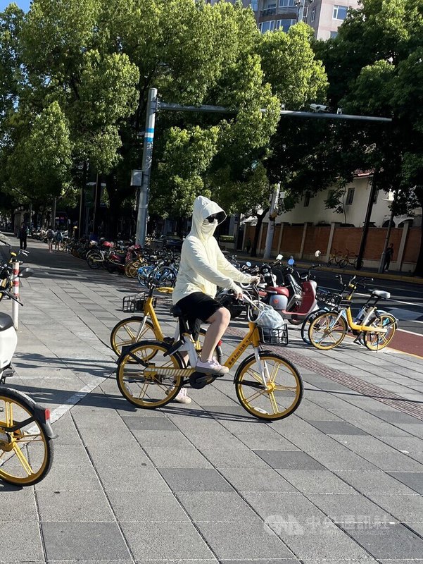 中國上海、江蘇、浙江受到副熱帶高壓影響，蒙受酷熱天氣襲擊，江浙滬3日上午拿下中國前10大高溫地區。圖為上海一名女子做好防曬措施騎乘自行車。中央社記者李雅雯上海攝 113年8月3日