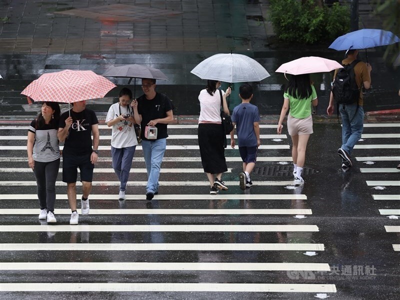 圖為台北市信義區商圈民眾撐傘過馬路。（中央社檔案照片）