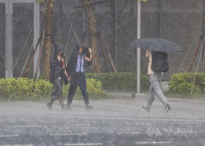 圖為台北市中正區街頭有民眾未帶雨具，在滂沱雨勢中以衣物擋雨。（中央社檔案照片）