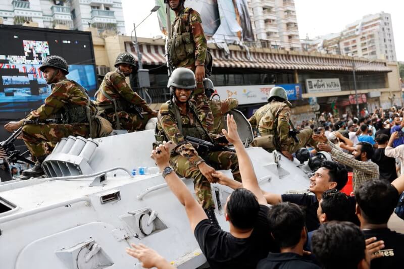 孟加拉民眾5日在總理哈希納下台後與軍人握手。（路透社）