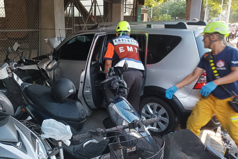 一輛銀色自小客車12日下午疑似由成功大學成功校區內高速開出校門，在大學路與一輛自小客車碰撞後撞進騎樓，一路波及多輛機車，其中1名女性機車騎士當場死亡。圖為消防人員趕抵救援。（讀者提供）中央社記者楊思瑞台南傳真 113年8月12日