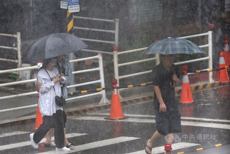 台北市松山區民眾撐傘快步躲雨。（中央社檔案照片）