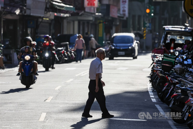 圖為台北市內湖區民眾橫跨馬路，步行至陰影處。（中央社檔案照片）