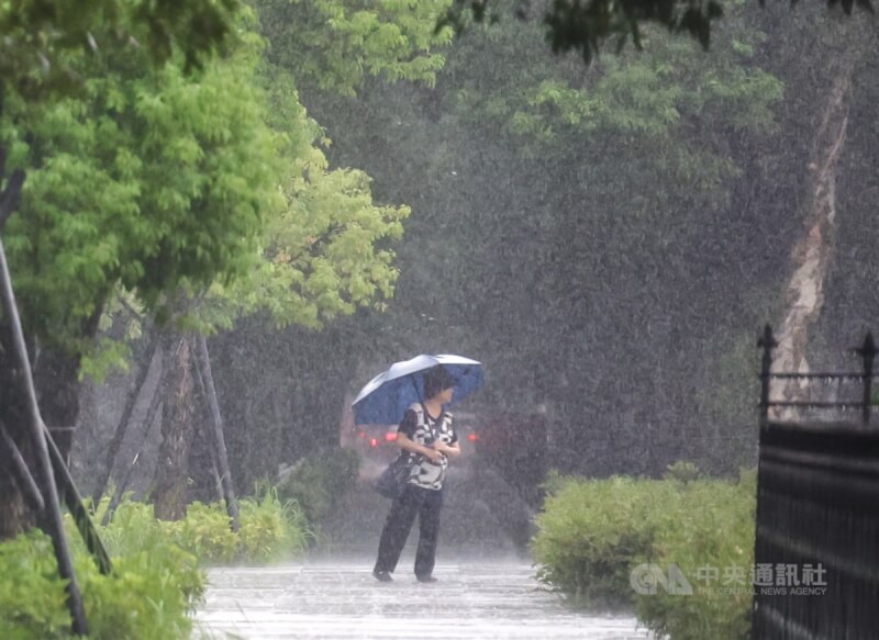 圖為台北市信義區街頭有民眾撐傘走在大雨中。（中央社檔案照片）