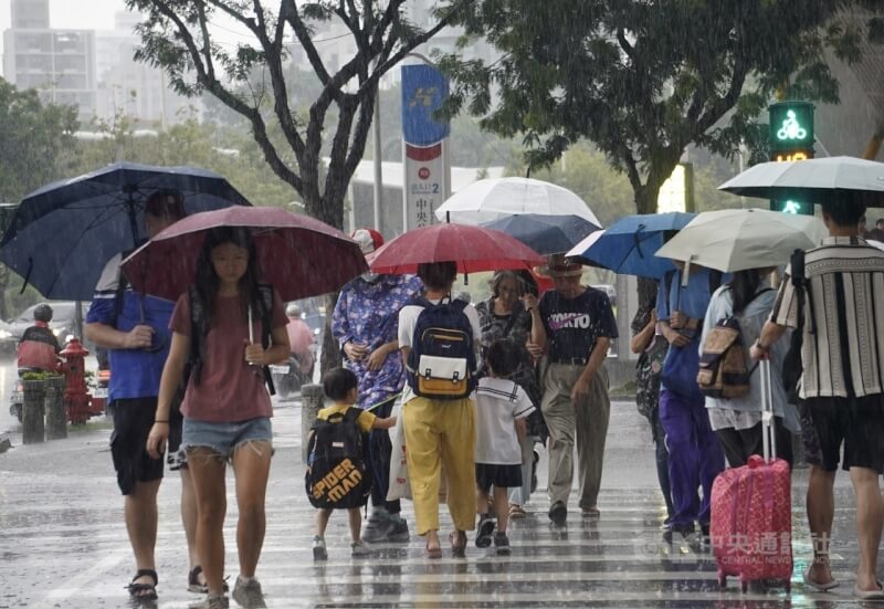 圖為高雄市新興區民眾撐雨過馬路。（中央社檔案照片）