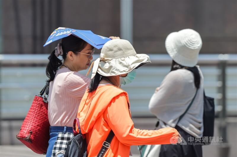 圖為民眾中午至台北市信義區，在戶外走動時用宣傳單遮陽。（中央社檔案照片）