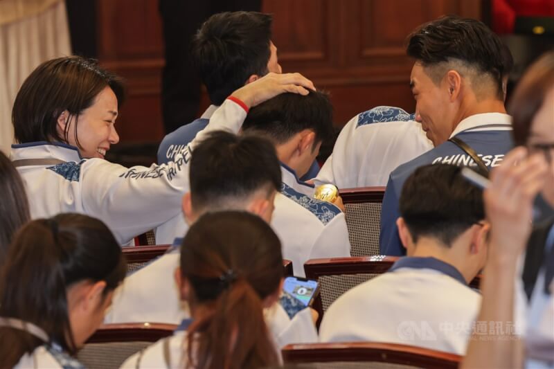 「Our Heroes！Team Taiwan 台灣英雄 榮耀同行」活動16日登場，巴黎奧運代表團在等待總統接見時，柔道好手楊勇緯（後中持獎牌者）低頭仔細欣賞拳后林郁婷借他的金牌，「柔道女王」連珍羚（後左）則在旁摸頭安慰他。中央社記者裴禛攝 113年8月16日