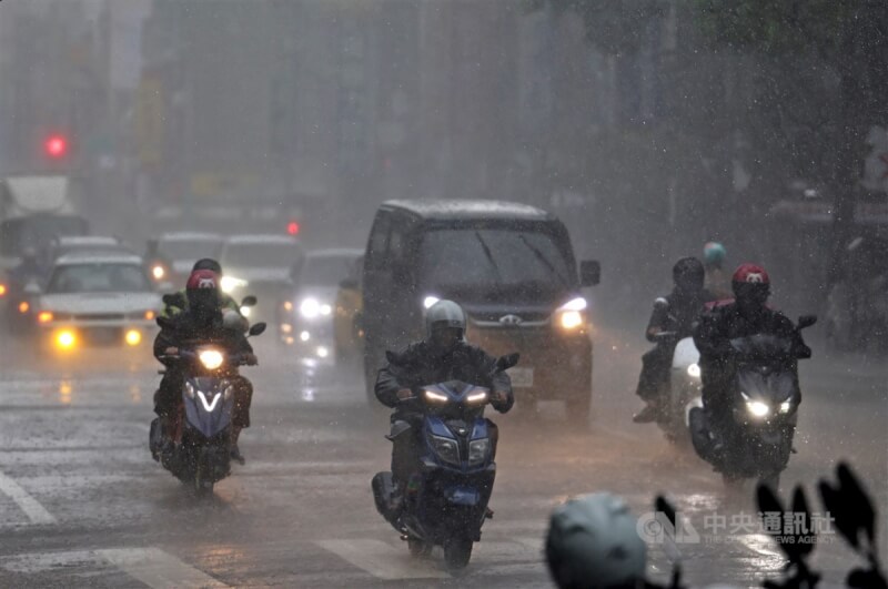 圖為台北市松山區午後下大雨，騎士冒雨騎車前行。（中央社檔案照片）