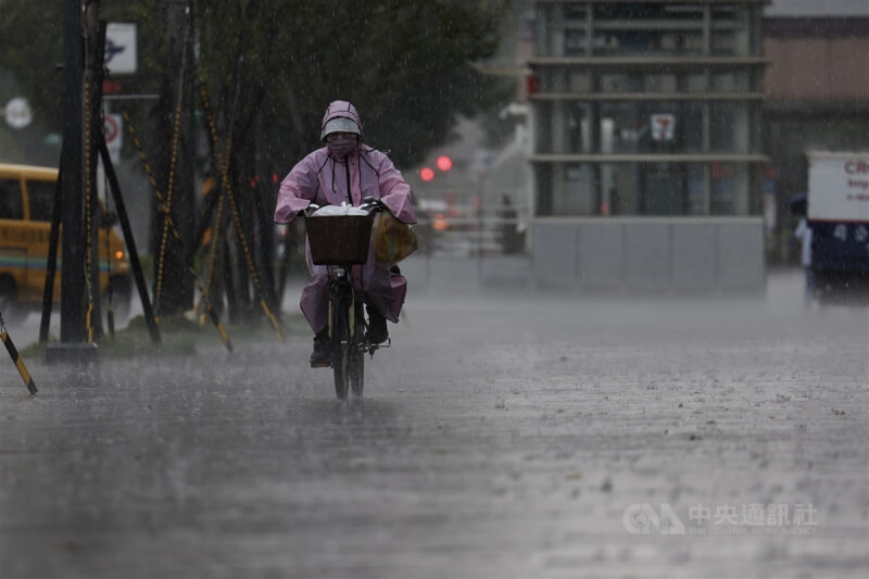 圖為台北市午後下起一陣大雨，信義區民眾穿雨衣騎腳踏車。（中央社檔案照片）