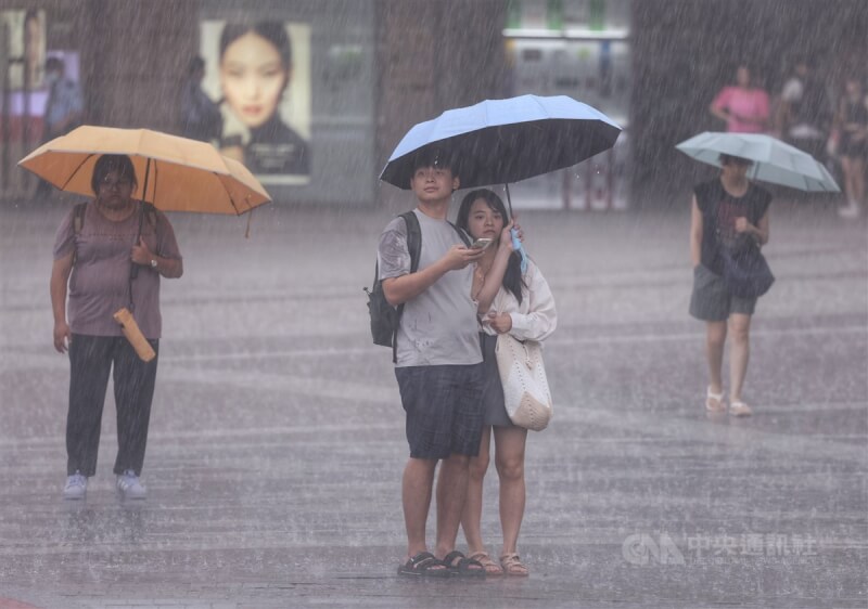 圖為台北市大直區民眾撐傘駐足在滂沱雨勢中。（中央社檔案照片）