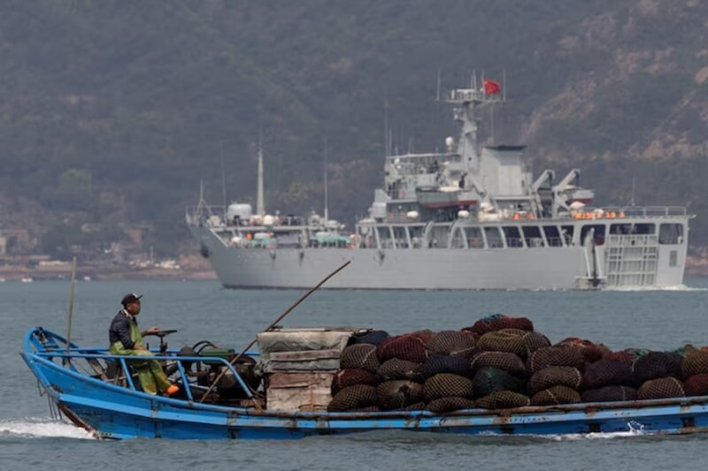 圖為去年4月中國福州漁船駛過一艘中國軍艦。（路透社）