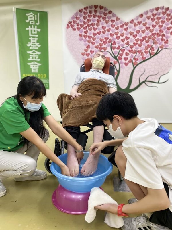 53歲葉先生(中)是名單親爸爸,原本與兒子、70多歲的母親相依為命,卻因一場意外成為植物人,12歲葉小弟(右)日前來到創世基金會文山分院探望,為父親洗腳、按摩、穿上襪子,盼他有一天能醒來,場面溫馨。(創世基金會提供)中央社記者曾以寧傳真 113年8月29日