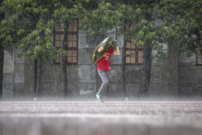 圖為松山文創園區有民眾沒帶雨傘，只能先以衣物遮擋雨勢、快步前進。（中央社檔案照片）