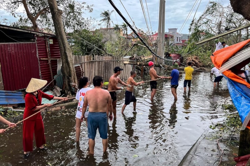 海防市路樹倒塌,民眾在樹上綁繩合力挪動。(路透社)