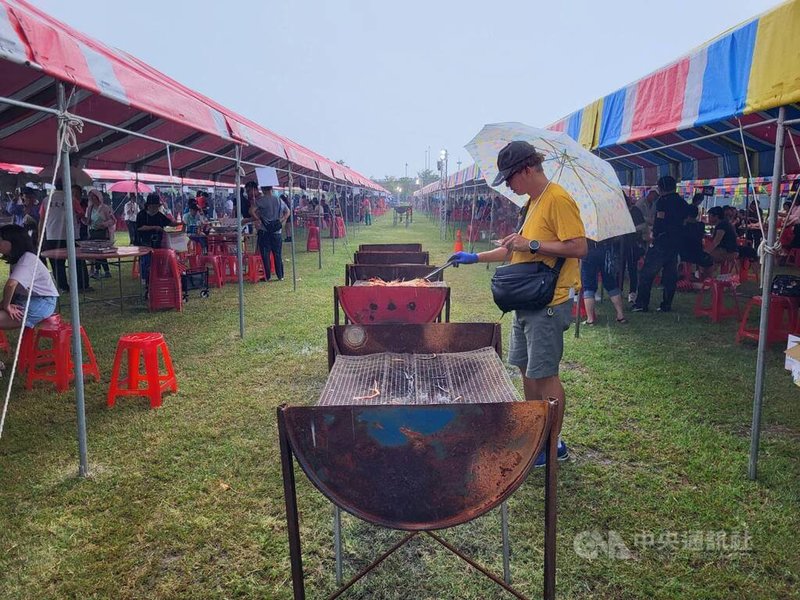 中秋節將至，屏東縣潮州鎮公所14日辦理「中秋神蝦大會烤」，約3000人在潮州鐵道園區共襄盛舉，儘管天公不作美，許多民眾仍不畏風雨撐著傘繼續烤蝦。中央社記者黃鬱菁攝  113年9月14日