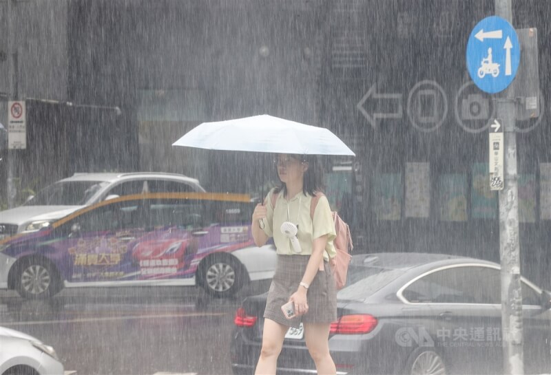 圖為台北市中正區雨勢滂沱，民眾撐傘擋雨。（中央社檔案照片）