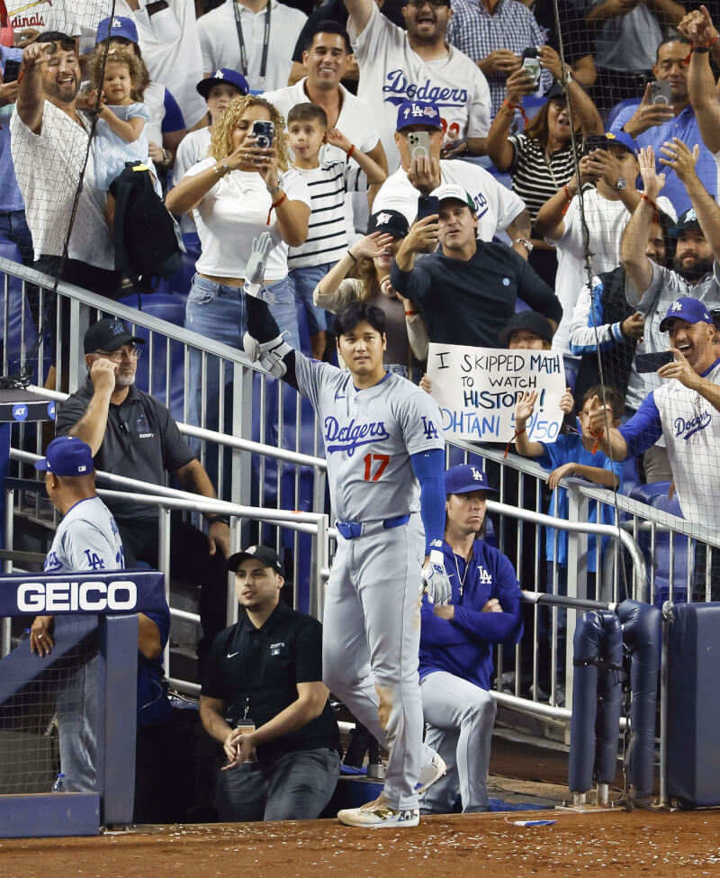 MLB洛杉磯道奇隊球星大谷翔平（中）達成「50轟50盜」里程碑後，回應現場觀眾歡呼。後方觀眾舉著標語寫著：「我翹了數學課來見證歷史」。（共同社）