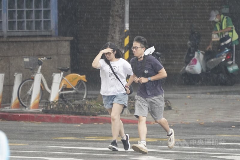 圖為台北市中正區，未攜帶雨具的民眾快步過馬路。（中央社檔案照片）