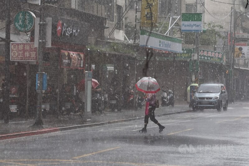 台北市內湖區出現間歇性雨勢，民眾撐傘過馬路。中央社記者翁睿坤攝 113年9月29日