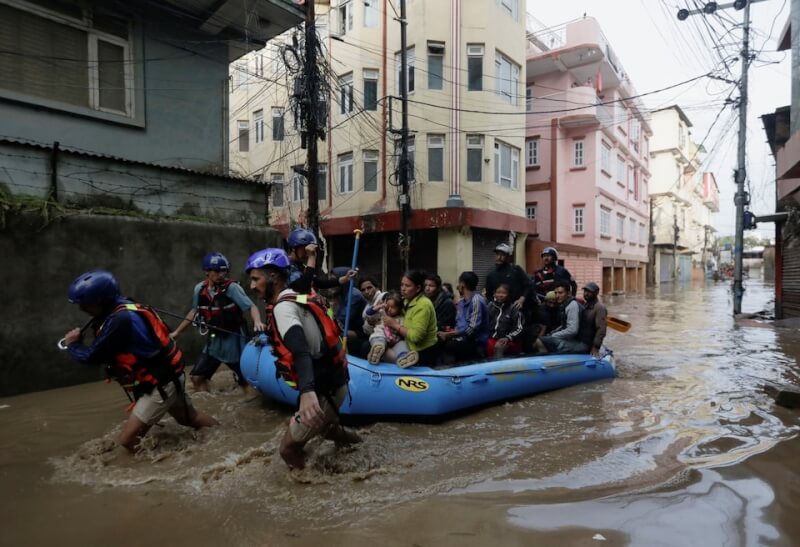 強烈降雨襲擊尼泊爾，圖為加德滿都搜救人員用充氣救生筏帶民眾至安全區域。（路透社）