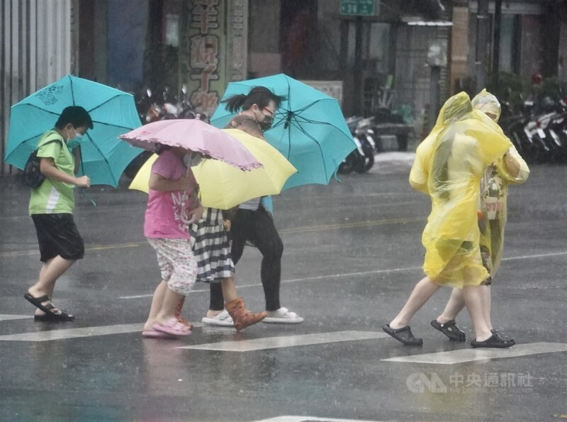 圖為高雄市苓雅區2日午後風雨轉強，街頭民眾穿著雨衣、撐傘在強風雨勢中前行。中央社記者董俊志攝 113年10月2日