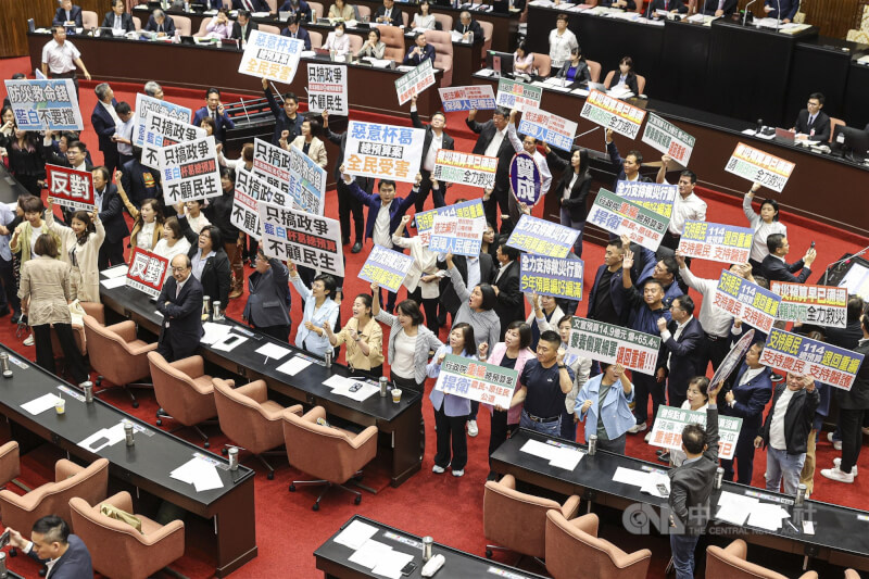 國民黨、民眾黨立委4日再度聯手，將114年度中央政府總預算案退回程序委員會。圖為表決過程中，民進黨立委於議場中舉牌「只搞政爭、不顧民生、惡意杯葛、全民受害」，高呼「藍白不要擋」。中央社記者鄭清元攝 113年10月4日