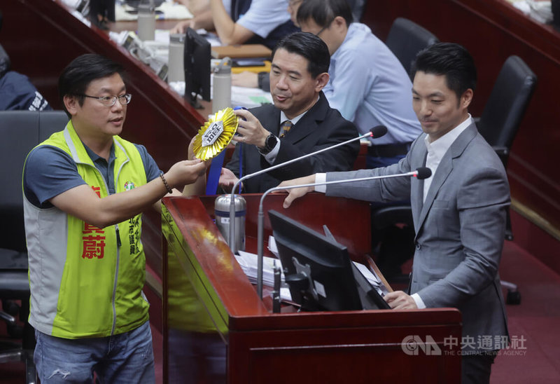 台北市長蔣萬安（右）8日赴議會施政報告，民進黨議員陳賢蔚（左）指出，近期對蔣萬安印象就是喜歡蹭，如以4首歌慰留副市長李四川，市政議題則以罐頭式回應，並送上寫有「蹭」的大型金牌。中央社記者裴禛攝  113年10月8日