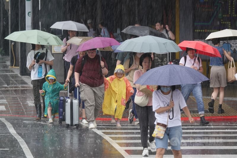 中央氣象署表示9日基隆北海岸及臺北市、宜蘭縣山區將有局部大雨或豪雨。圖為台北市中山區民眾撐傘、穿雨衣過馬路。（中央社檔案照片）