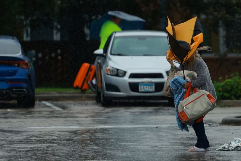 颶風密爾頓9日從佛羅里達州西岸登陸，一名女子走在路上雨傘開花。（路透社）