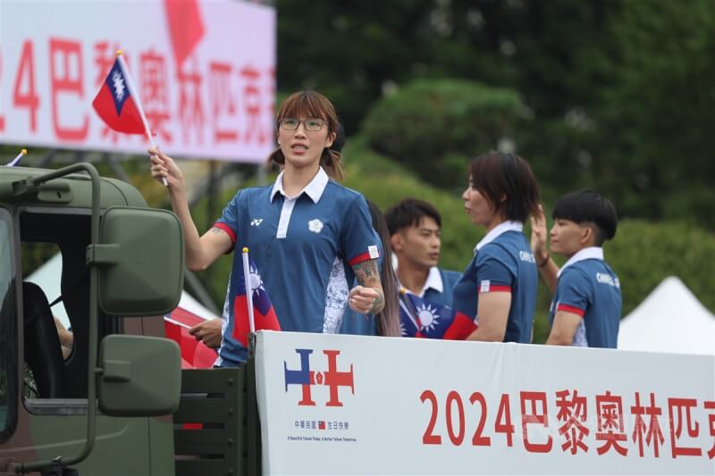 巴黎奧運女子拳擊選手黃筱雯(前左)等運動員隨著車隊揮舞國旗進場。中央社記者趙世勳攝 113年10月10日