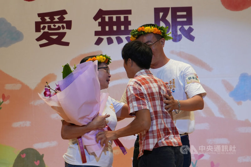 屏東縣政府27日表揚資深寄養家庭，安排寄養家庭爸媽與離開寄養兒少重逢。有20餘年資歷的郭梁秋香（左）接受多重障礙兒砂沙獻花，感動落淚。中央社記者黃郁菁攝 113年10月27日