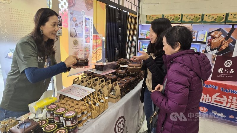 許多民眾對來自客家山城的豆腐乳和桂花釀很感興趣,桂花品公司經理黃敏媛(左)細心地向民眾說明依循傳統古法釀製出的好味道。中央社記者程愛芬溫哥華攝 113年10月27日