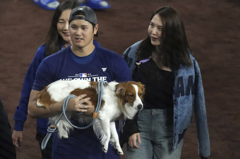 大谷翔平（前左）、妻子田中真美子（前右）與愛犬彈額頭。（美聯社）