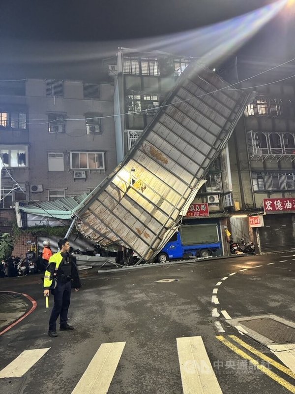 颱風康芮襲台，新北市新莊區仁愛街31日晚間有大片鐵皮屋頂遭強風吹落後，整片緊貼公寓大樓外牆，警方獲報到場協助引導交通，警示用路人。（翻攝照片）中央社記者高華謙傳真  113年10月31日