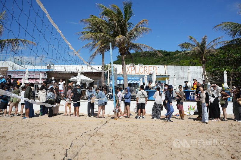 以拍攝公益月曆聞名全球的澳洲消防員2日在墾丁南灣與屏東消防員進行沙灘排球友誼賽,澳洲消防員現場發放海報,吸引民眾排隊索取。中央社記者黃郁菁攝 113年11月2日