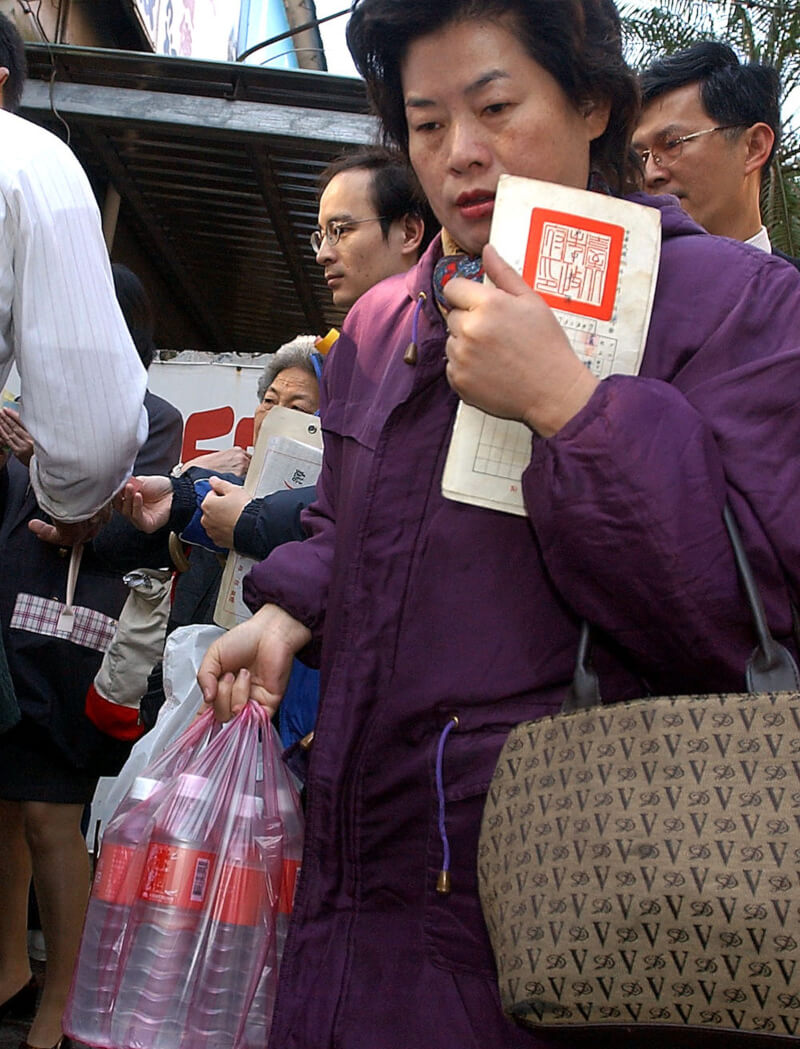 台灣加入世界貿易組織前夕,引起搶購低價米酒風潮,民眾大排長龍以戶口名簿購買米酒。中央社記者孫仲達攝 90年12月31日