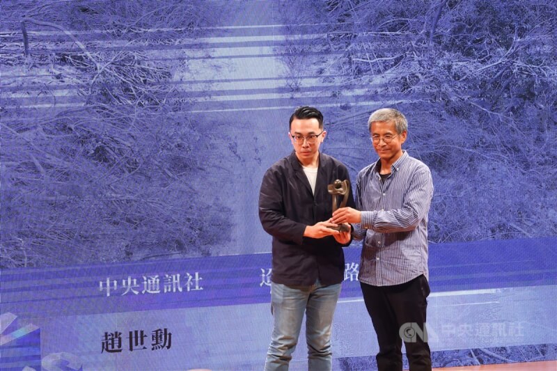 第23屆卓越新聞獎19日在台北舉行頒獎典禮,中央社攝影記者趙世勳(左)以「迢迢回家路」獲得單張新聞攝影獎,從評審黃子明(右)手中接過獎座。中央社記者王騰毅攝 113年11月19日