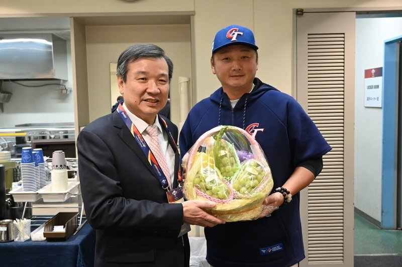 世界12強棒球賽複賽明天東京巨蛋登場,台灣隊20日下午在東京巨蛋簡單練習,駐日代表李逸洋(左)到場探班打氣,致贈麝香葡萄,台灣隊總教練曾豪駒(右)表達謝意。(駐日代表處提供)中央社記者楊明珠東京傳真 113年11月20日