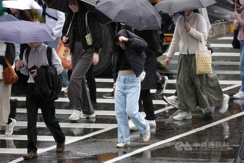 圖為台北市南港軟體園區民眾用外套遮擋雨勢。（中央社檔案照片）