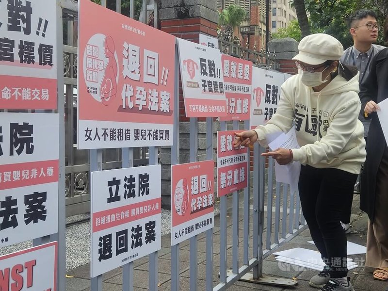 立法院社會福利及衛生環境委員會5日審查「人工生殖法」修正草案，台灣反代孕行動小組等多個婦女團體在場外抗議，不滿強審社會沒有共識的制度，參與者在立法院門口貼抗議口號，要求退回法案。中央社記者陳婕翎攝  113年12月5日