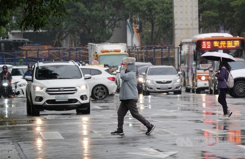 圖為台北市南港軟體園區民眾舉起物品放在頭上遮雨。（中央社檔案照片）