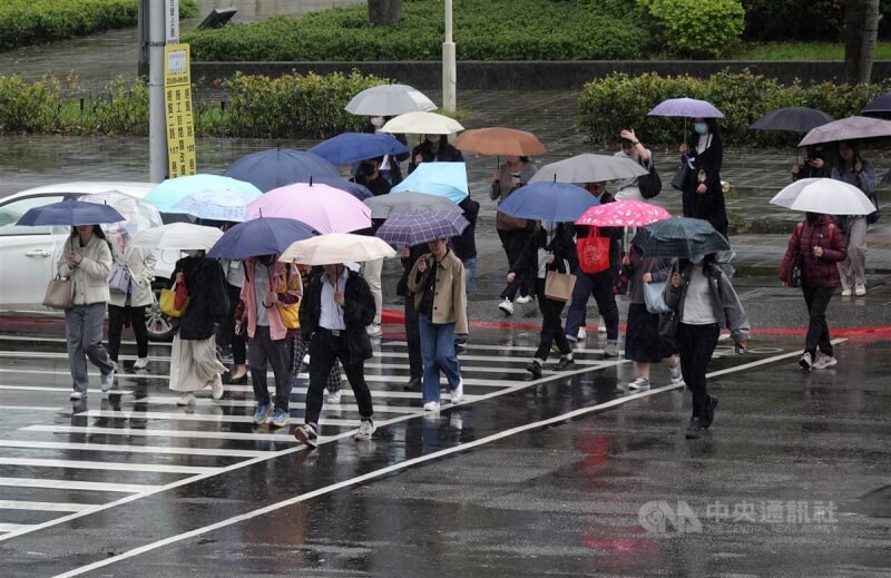 圖為台北市南港軟體園區上班族撐傘過馬路。（中央社檔案照片）