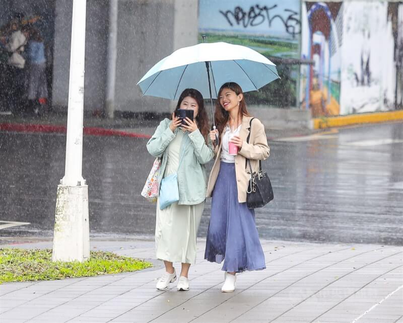 圖為台北市中正區街頭民眾穿著長袖衣物撐傘擋雨。（中央社檔案照片）